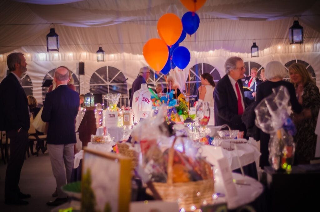 A candid photograph of raffle prize tables and guests at a formal event.