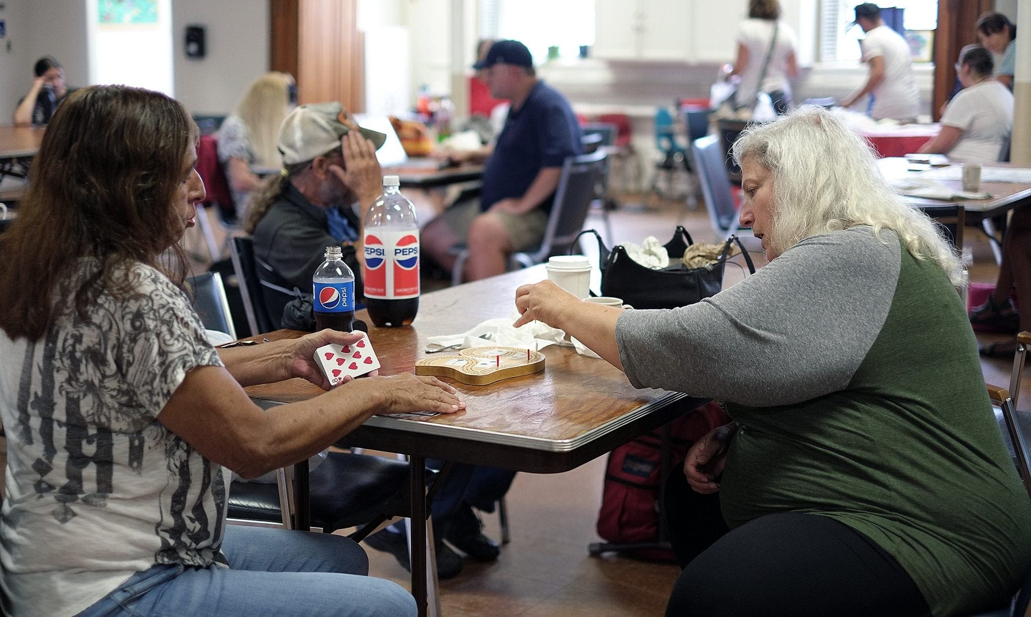 Two women play a card game at a table.