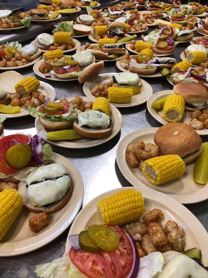 A photograph of plates assembled ith burgers, tater tots, and corn-on-the-cob.