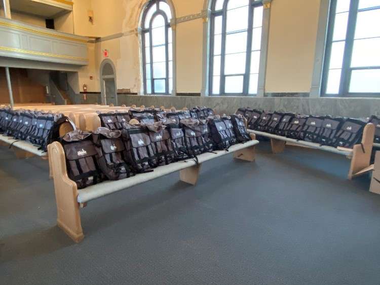 A photograph of CityPack backpacks arranged on church pews.