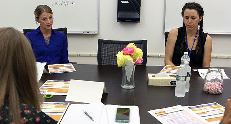 Two women sitting at a conference table.