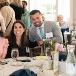 A group of guests smile at the camera while seated at a table at "Together for Women"