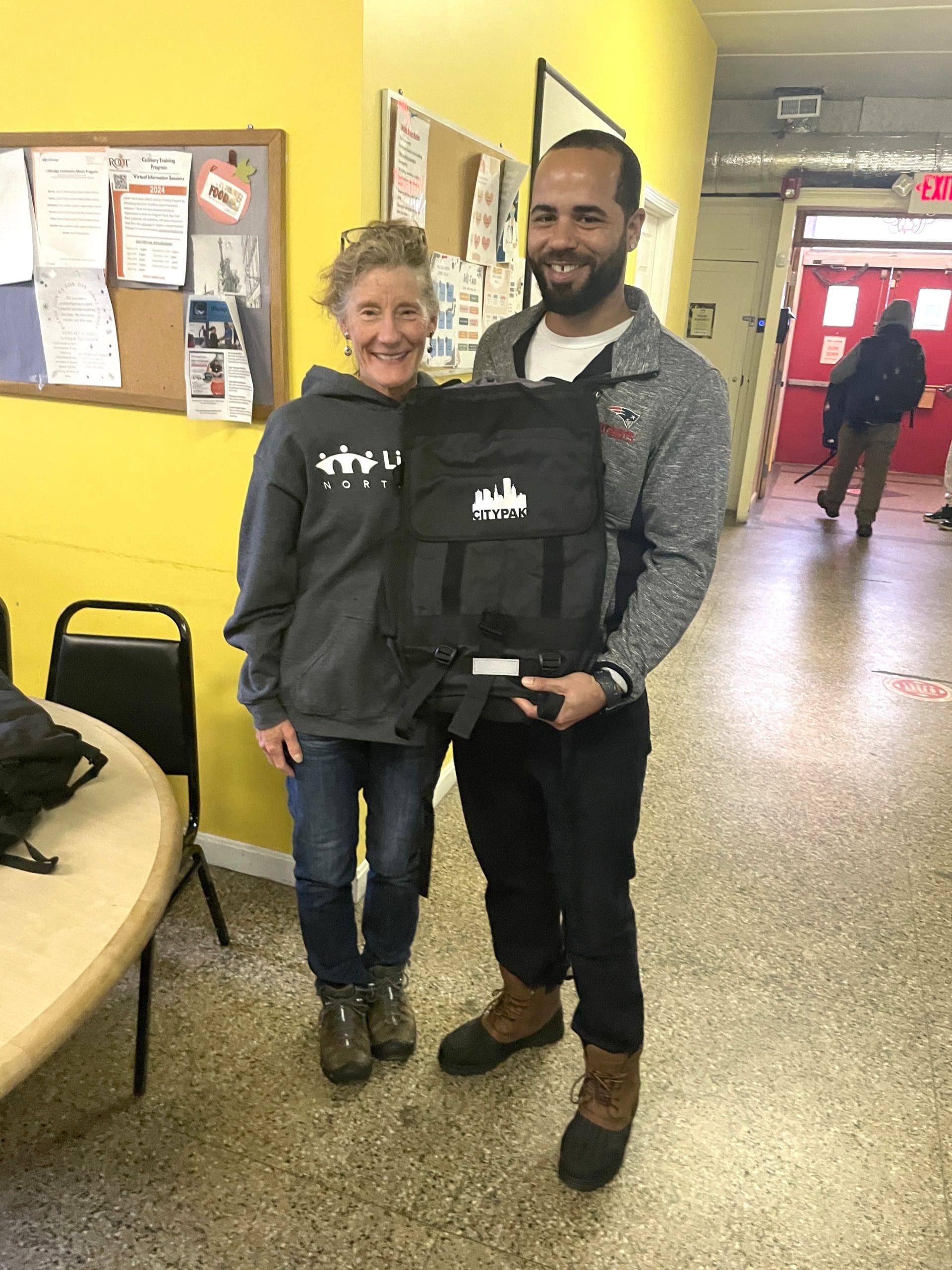A man and woman pose with a CityPack backpack.