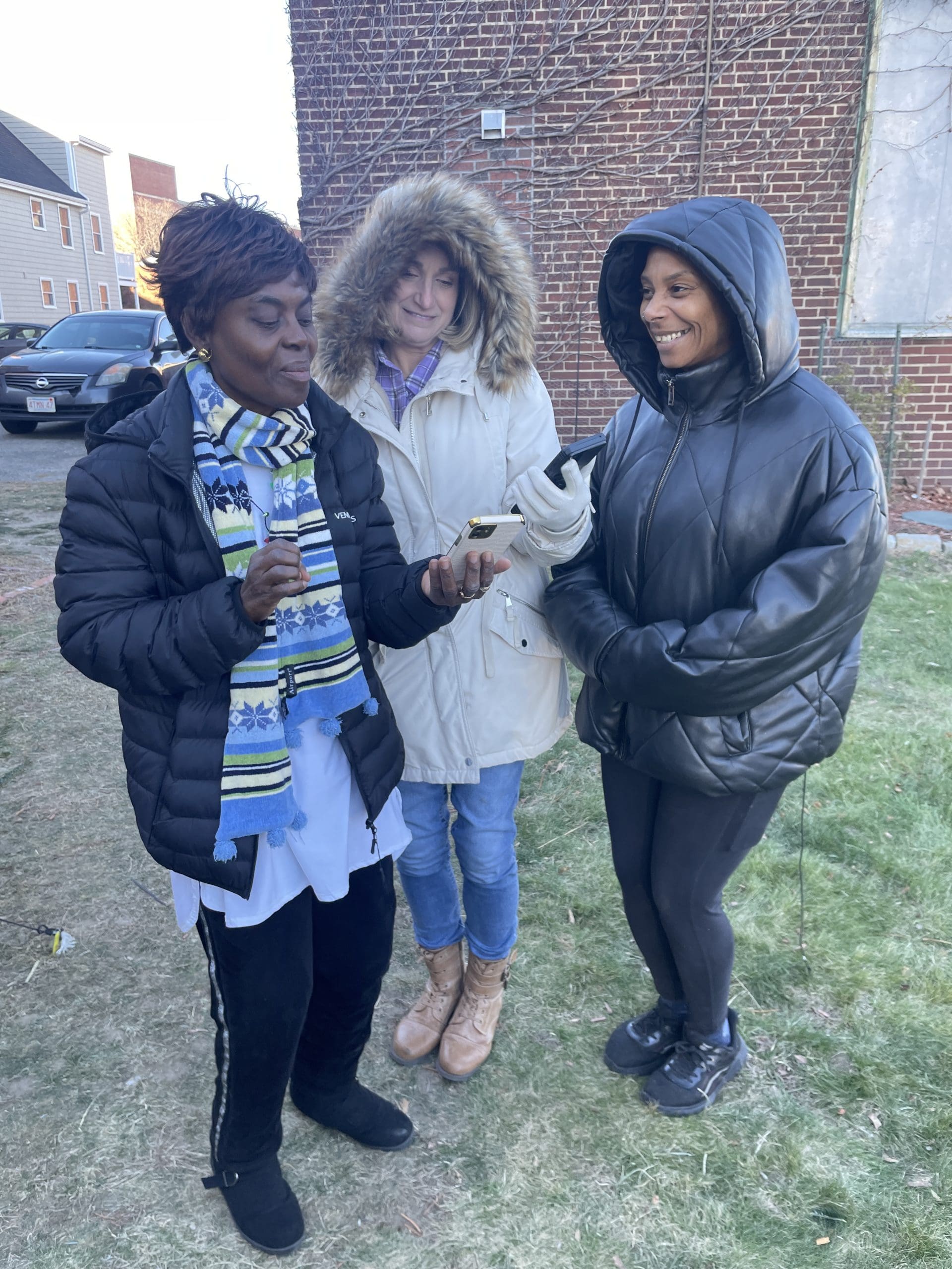 Three women standing looking at pictures on a phone