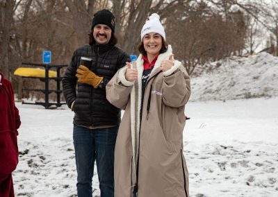 Two people smiling at the camera in their jackets and beanies.