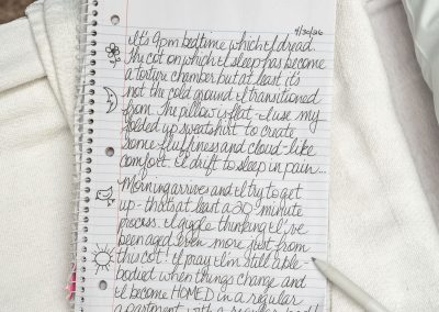 Close up of a notebook with cursive writing on it and a pen next to it.