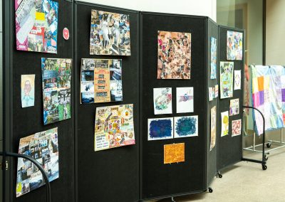 A black accordion-style display board with various pieces of artwork.