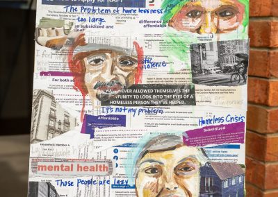The photograph displays a square mixed-media collage poster presented on a black metal artist easel [image_P6JW1P.png]. The artwork layer combines printed official application forms and housing documents with expressive hand-painted portraits and handwritten annotations [image_P6JW1P.png]. The piece visually addresses the bureaucratic and human struggles surrounding the homeless crisis, housing assistance, and mental health