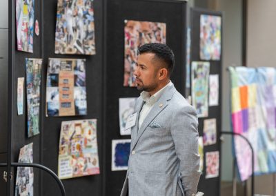 The image shows a candid indoor photograph of a man viewing an art exhibition or project display.