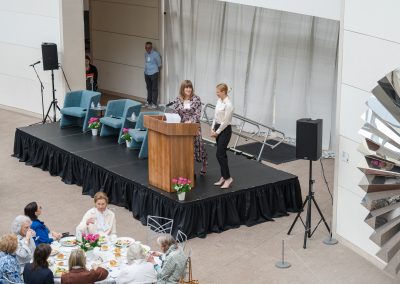 Photograph provides a high-angle, wide establishing shot of the entire main stage area and an adjacent guest table during the formal charity event.
