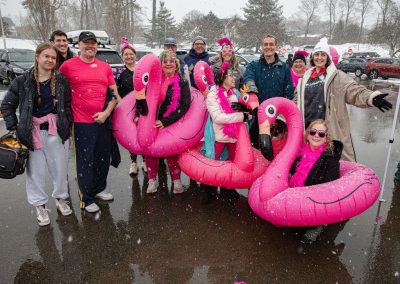 A group of people in pink flamingo floaties posing together for a team photo.