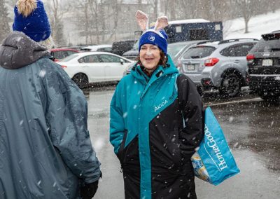Woman in a jacket, beanie, and rabbit ears standing in the snow.