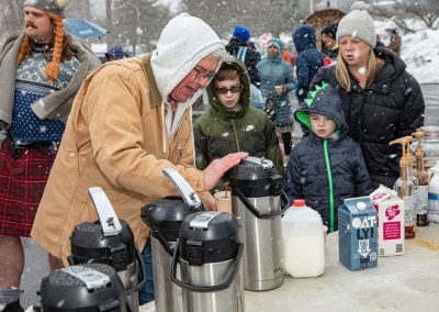 Man getting coffee at the coffee table, with two little boys and woman waiting in line.