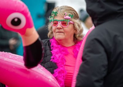 Woman in pink flamingo and palm tree sunglasses with a pink boa.