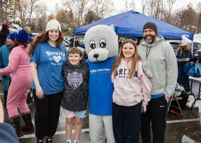 A family smiling and posing for a picture with the shoebert mascot.