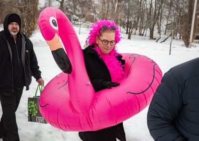 Woman in pink flamingo floaty, pink boa, and and pink sunglasses.