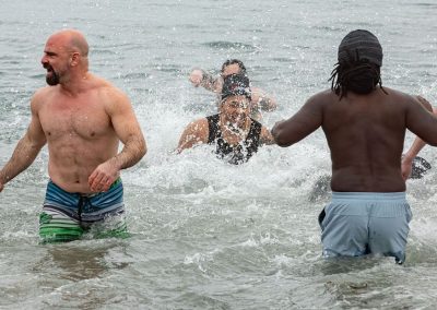 Four participants in their swimsuits splashing in the water.