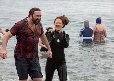 Man and Woman smiling and clapping coming out of the water.