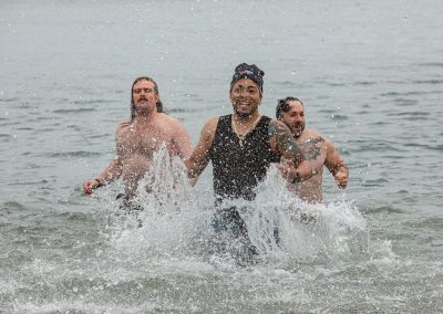 Three participants in their swimsuits splashing in the water.