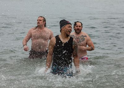 Three participants in their swimsuits splashing in the water.