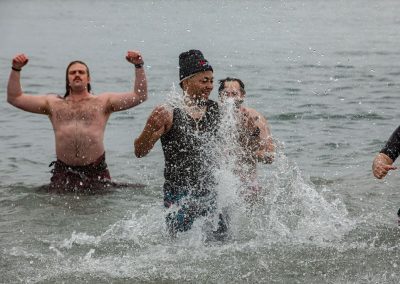 Three participants in their swimsuits splashing in the water and posing for the camera.