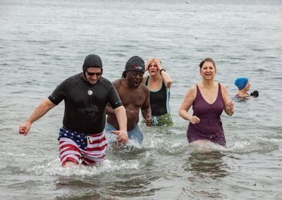 Four participants in their swimsuits walking out of the water.