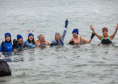 Seven woman huddling together in the water smiling and posing for the camera.