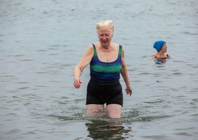 Woman coming out of the water. With a person floating in the background.
