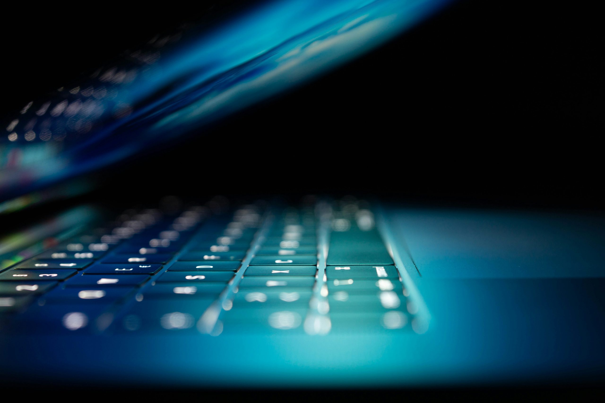 A laptop in a is half-open with the screen illuminating the keyboard.